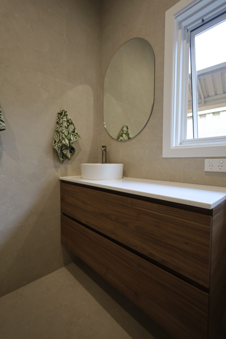 Vanity with an oval mirror and floor-to-ceiling tiling in a Floreat bathroom renovation, Perth