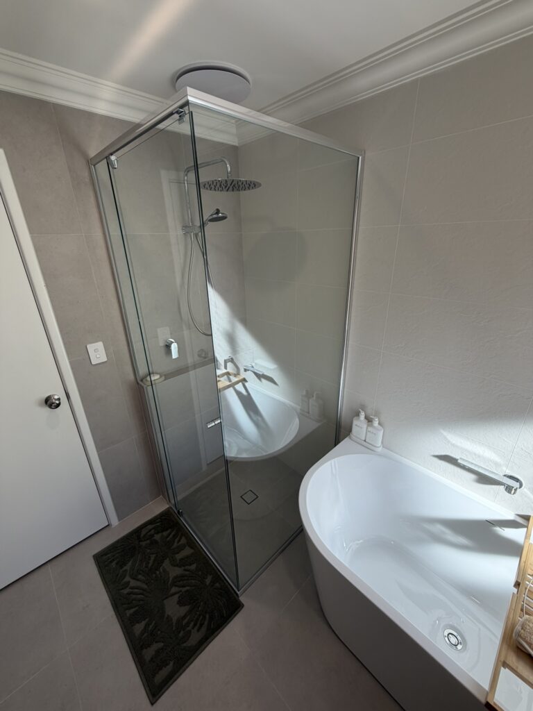 Clean glass shower screen beside a freestanding bath in an Atwell bathroom renovation, Perth